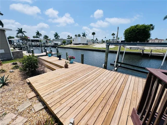 Waterfront property with an expansive wooden dock, boat lift structure, and established landscaping