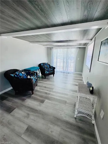 Wood-finish flooring throughout, light gray walls, and a wood-finish ceiling with exposed white beams