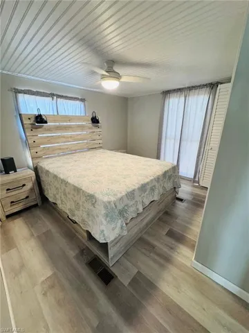Wood-finish flooring, beadboard ceiling, ceiling fan with integrated lighting, window treatments, and louvered bifold closet doors