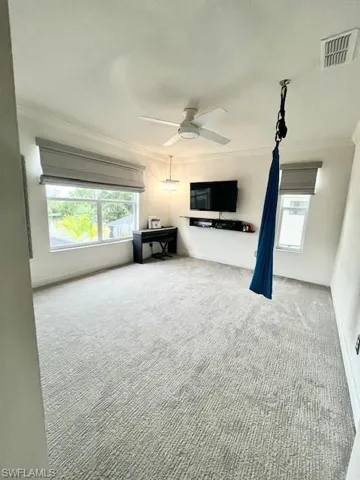 Unfurnished living room featuring healthy amount of natural light, crown molding, carpet, ceiling fan, and a textured ceiling