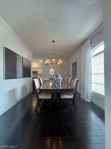 Dining room featuring crown molding, dark wood finished floors, and a chandelier