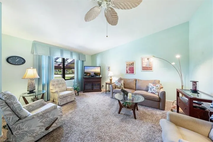 Living room featuring lofted ceiling, carpet floors, and ceiling fan