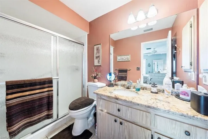 Bathroom with vanity, ceiling fan, toilet, a shower with door, and tile patterned flooring