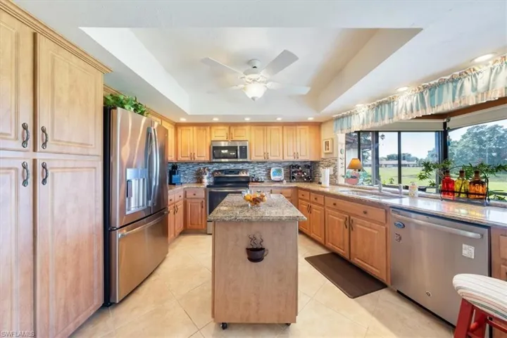 Kitchen with stainless steel appliances, a raised ceiling, and tasteful backsplash