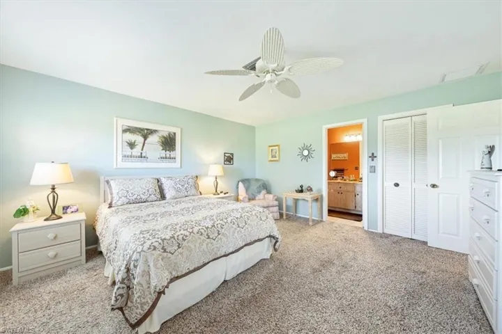 Carpeted bedroom with ensuite bath, ceiling fan, and a closet