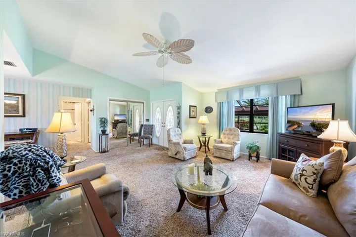 Living room featuring carpet floors, ceiling fan, and vaulted ceiling