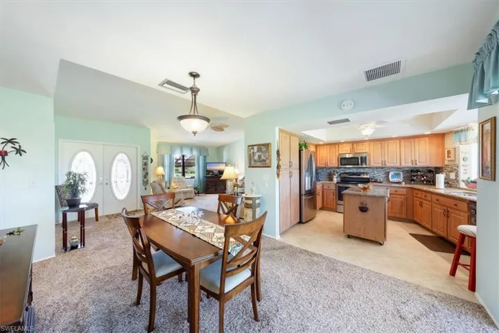Dining room with sink, french doors, ceiling fan, light tile patterned floors, and a tray ceiling