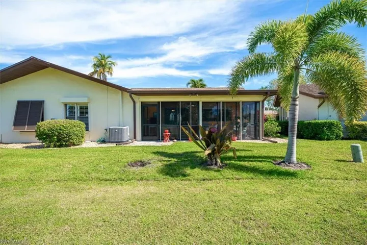 Back of house featuring a sunroom, central air condition unit, and a yard