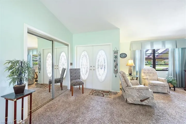 Carpeted foyer featuring vaulted ceiling