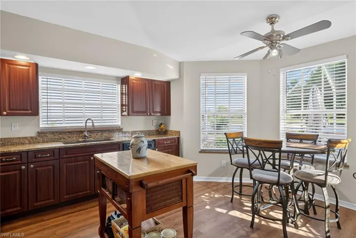 Kitchen with dark stone countertops, wood finished floors, recessed lighting, dark brown cabinets, and a ceiling fan