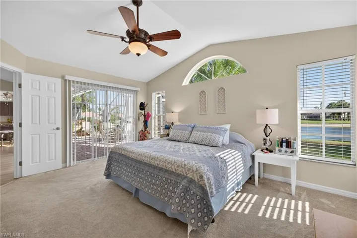 Carpeted bedroom with access to exterior, a ceiling fan, and vaulted ceiling