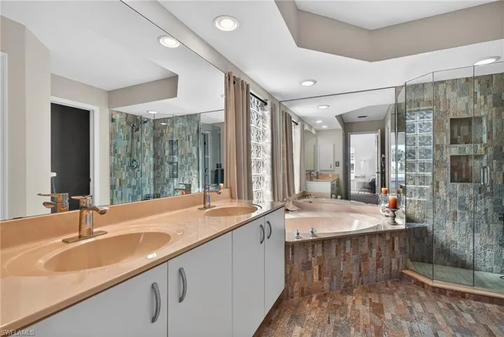 Bathroom with a shower stall, double vanity, a garden tub, and recessed lighting