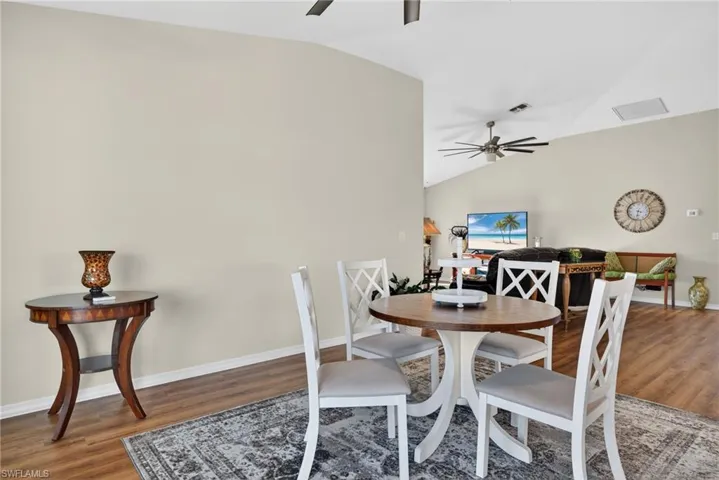 Dining area with lofted ceiling, light wood finished floors, and a ceiling fan