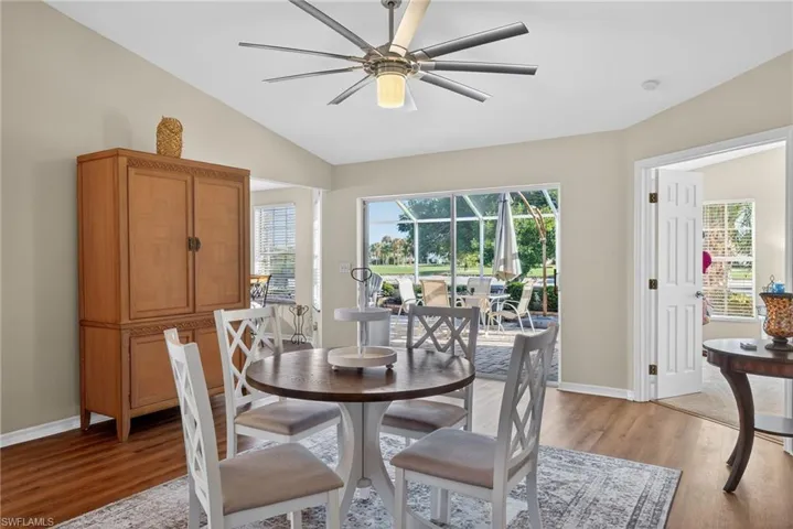 Dining room with vaulted ceiling, a ceiling fan, a sunroom, and light wood-style flooring