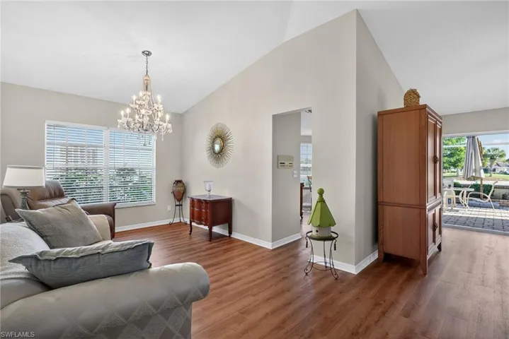 Living room with wood finished floors, a chandelier, and high vaulted ceiling