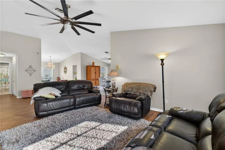 Living room featuring wood finished floors, a chandelier, lofted ceiling, and a ceiling fan