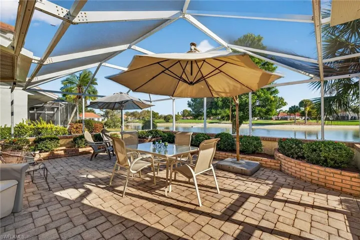 View of patio / terrace with screen enclosure, a sunroom, outdoor dining space, and a water view