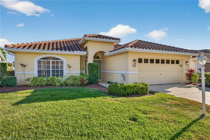 Mediterranean / spanish house with a front yard, stucco siding, concrete driveway, and a garage