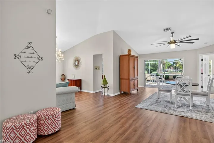 Dining area featuring wood finished floors, high vaulted ceiling, a ceiling fan, and a chandelier