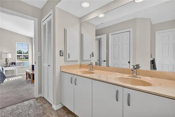 Full bathroom with a closet, double vanity, and vaulted ceiling