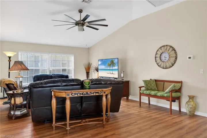 Living room featuring lofted ceiling, wood finished floors, and ceiling fan