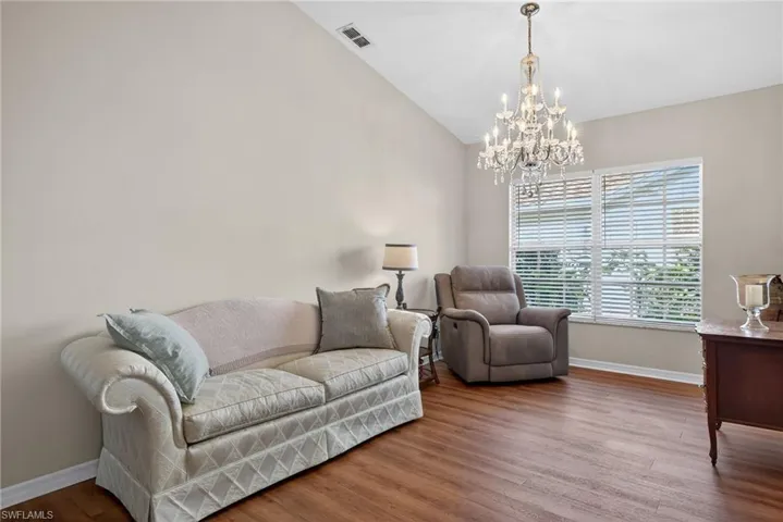 Living area featuring wood finished floors, lofted ceiling, and a chandelier