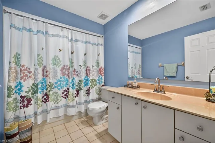 Full bathroom with vanity, curtained shower, and light tile patterned floors