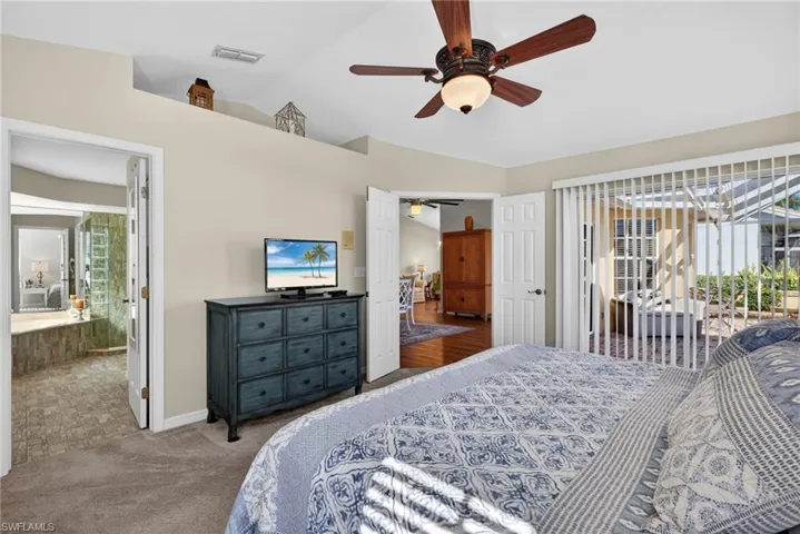 Bedroom featuring access to exterior, vaulted ceiling, a ceiling fan, carpet floors, and connected bathroom