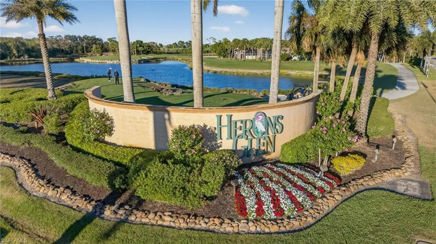 Community sign with a water view and view of wooded area