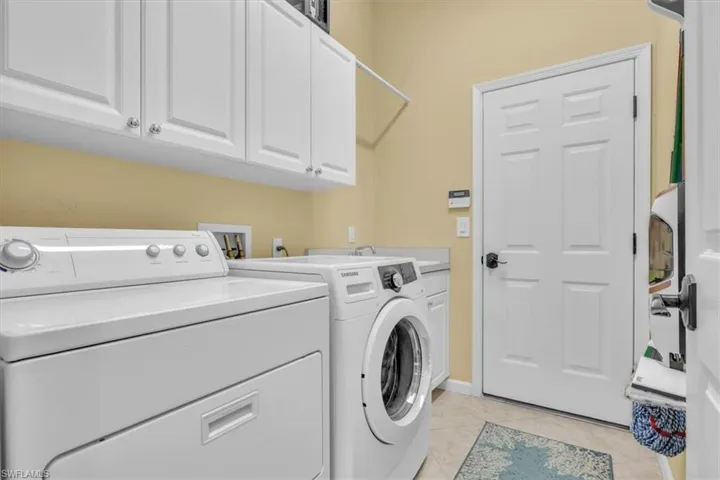 Laundry room featuring cabinet space, light tile patterned floors, and washer and dryer