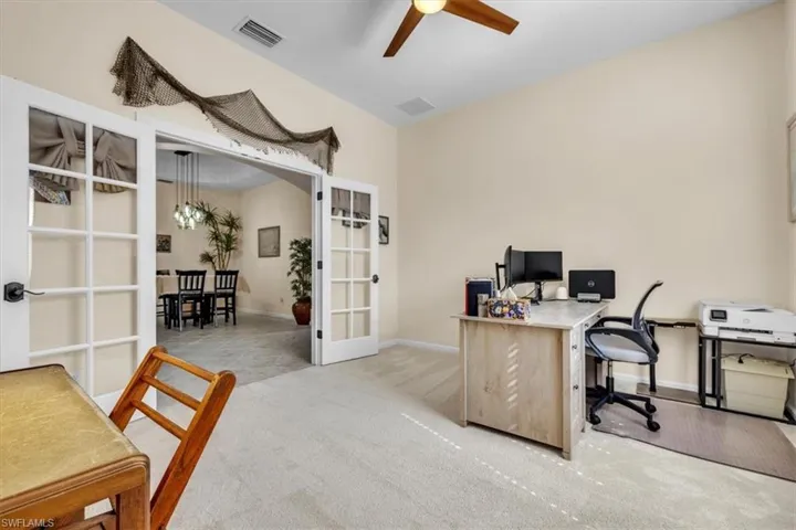 Office space with light colored carpet, french doors, ceiling fan, and arched walkways