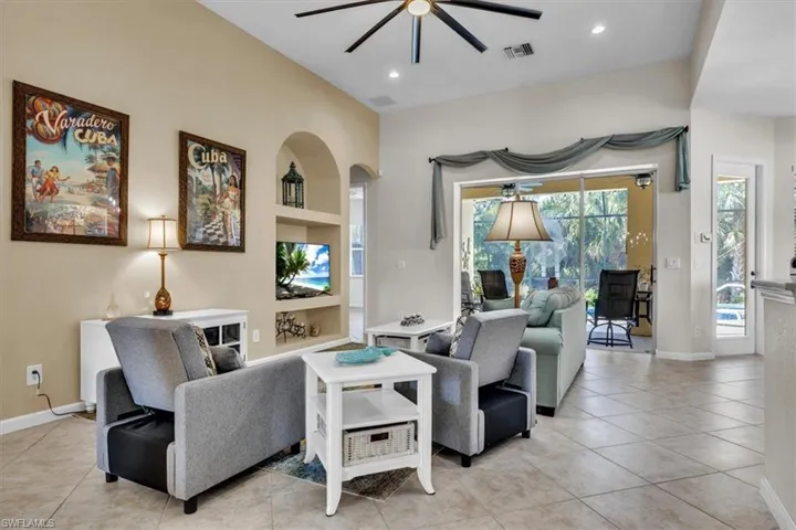 Living room featuring a ceiling fan, a sunroom, light tile patterned floors, built in features, and recessed lighting