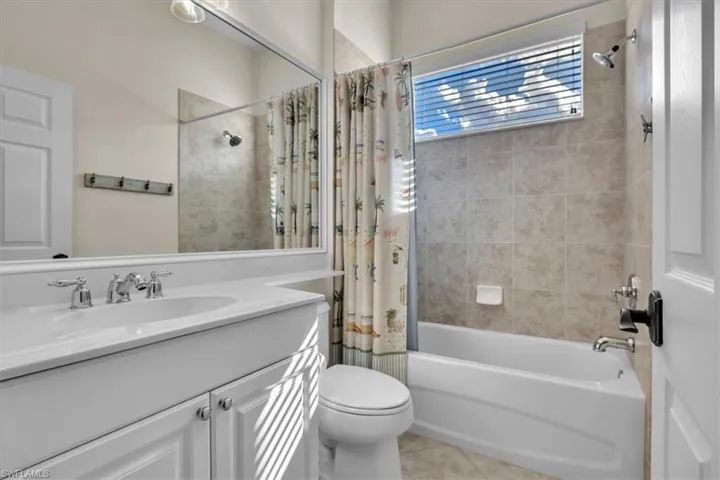 Bathroom featuring vanity, shower / bath combo, and light tile patterned flooring
