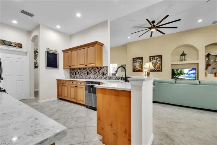 Kitchen with a peninsula, open floor plan, arched walkways, a ceiling fan, and dishwasher