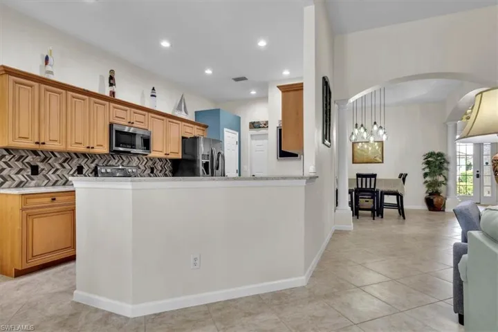 Kitchen featuring arched walkways, open floor plan, stainless steel appliances, a peninsula, and decorative backsplash