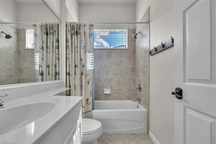 Full bathroom featuring vanity, shower / tub combo, light tile patterned floors, and plenty of natural light
