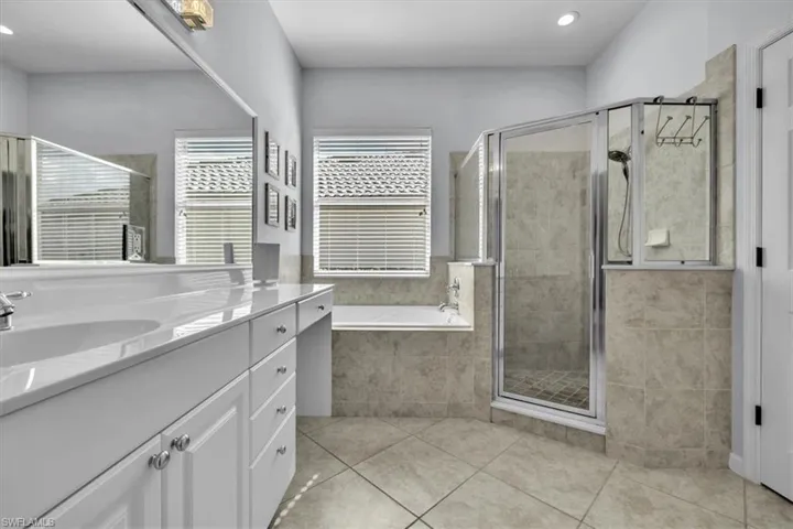 Bathroom with vanity, a bath, a stall shower, light tile patterned floors, and recessed lighting