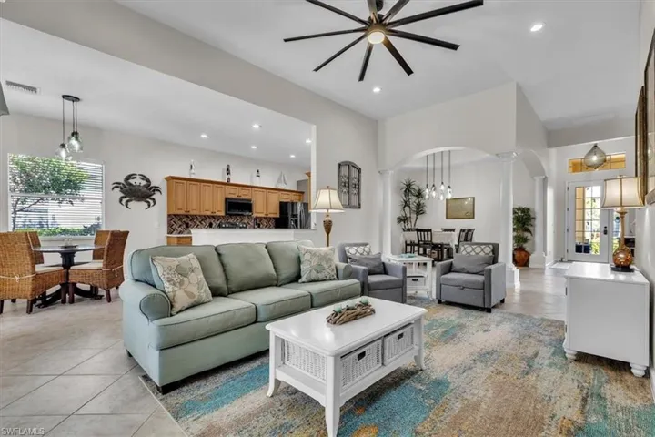 Living room with plenty of natural light, arched walkways, recessed lighting, ornate columns, and ceiling fan