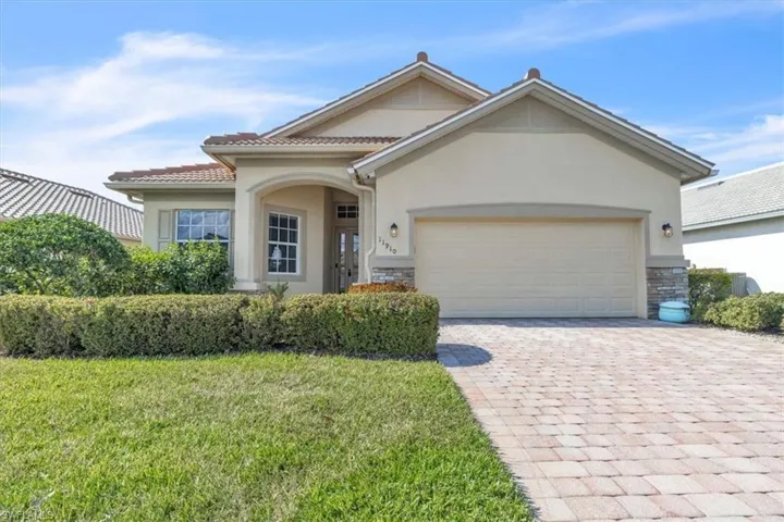 View of front of home with stone siding, a garage, stucco siding, decorative driveway, and a front yard