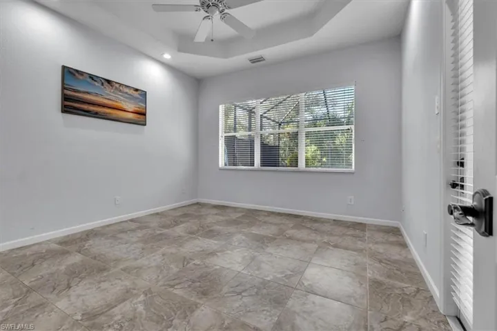 Unfurnished room featuring a ceiling fan, a raised ceiling, and recessed lighting