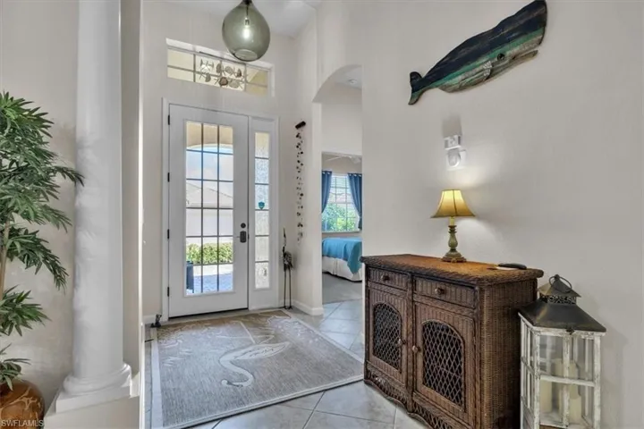 Foyer featuring arched walkways, a high ceiling, and light tile patterned floors