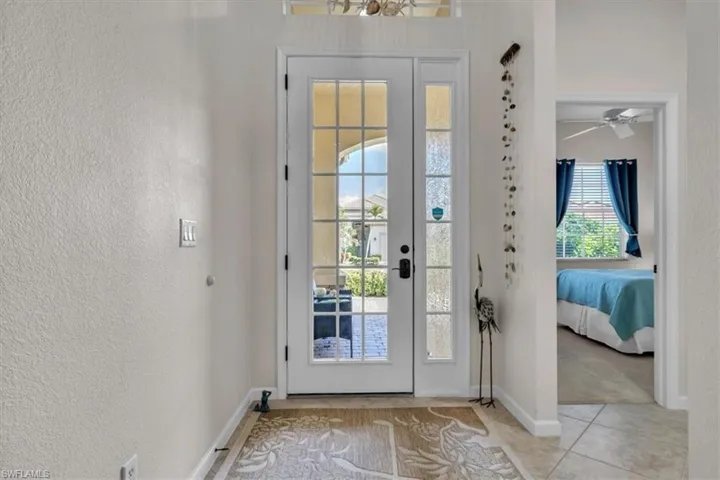 Doorway with a textured wall and ceiling fan
