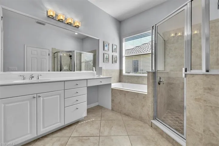 Bathroom with vanity, a stall shower, a garden tub, and light tile patterned flooring
