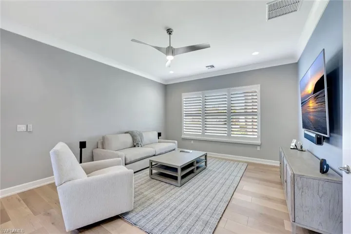 Living room with visible vents, light wood-style flooring, crown molding, and baseboards