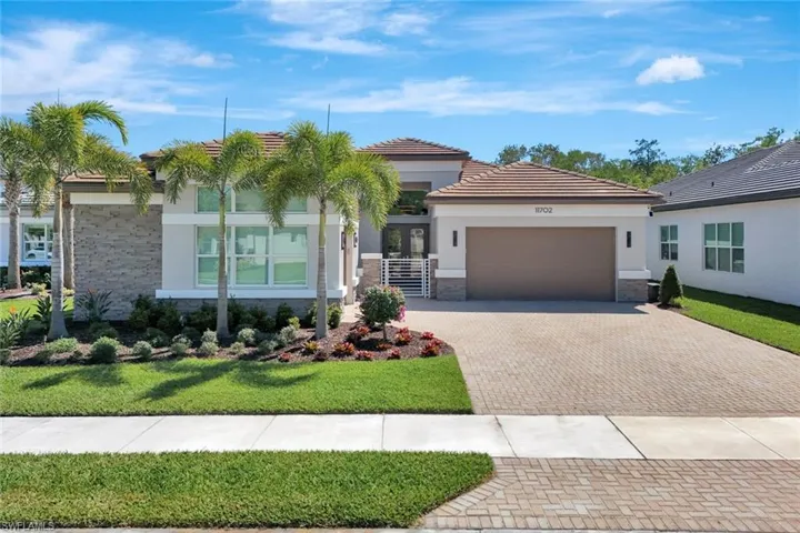 View of front facade with stucco siding, a front lawn, decorative driveway, stone siding, and an attached garage