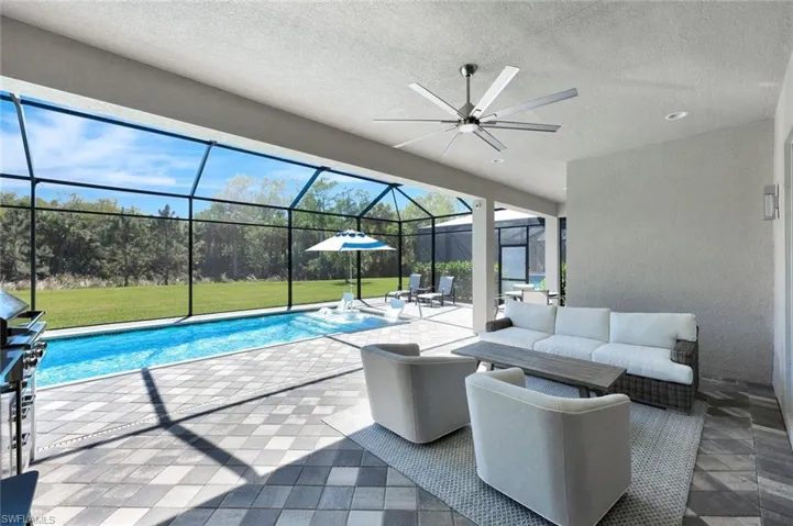 Outdoor pool with a lawn, ceiling fan, outdoor lounge area, a lanai, and a patio area