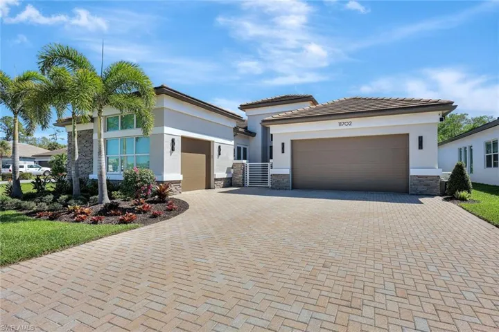 View of front facade featuring decorative driveway, stone siding, an attached garage, and stucco siding
