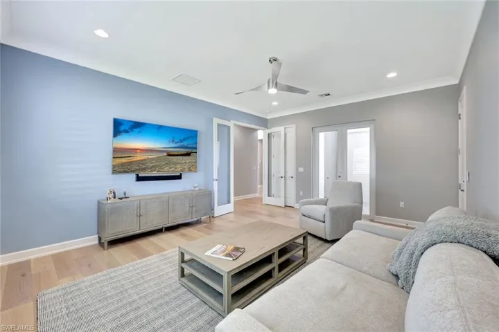 Living room featuring crown molding, french doors, baseboards, and light wood-type flooring