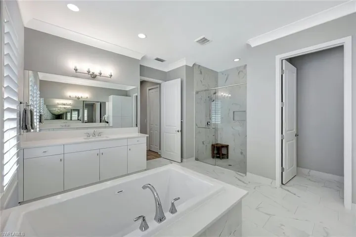Full bath featuring a marble finish shower, visible vents, crown molding, a garden tub, and marble finish floor