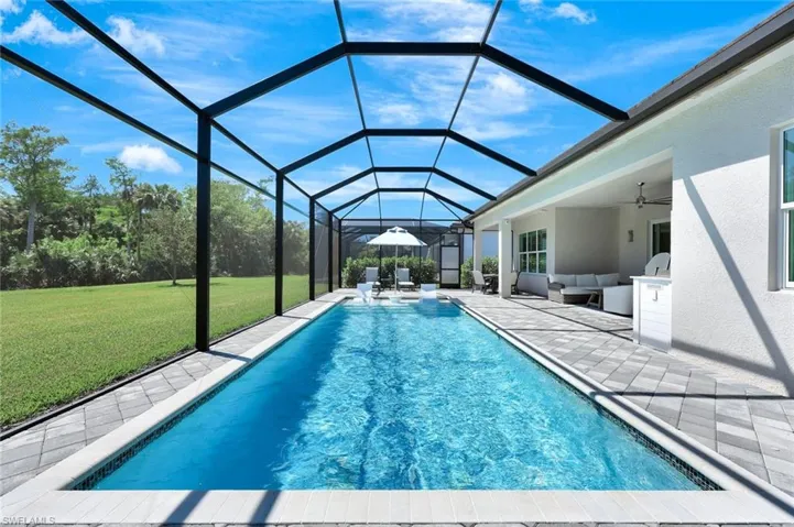 Pool with ceiling fan, glass enclosure, outdoor lounge area, a yard, and a patio area